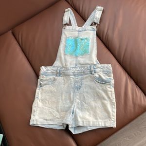 Bibbed overall shorts with flip sequin bib pocket.